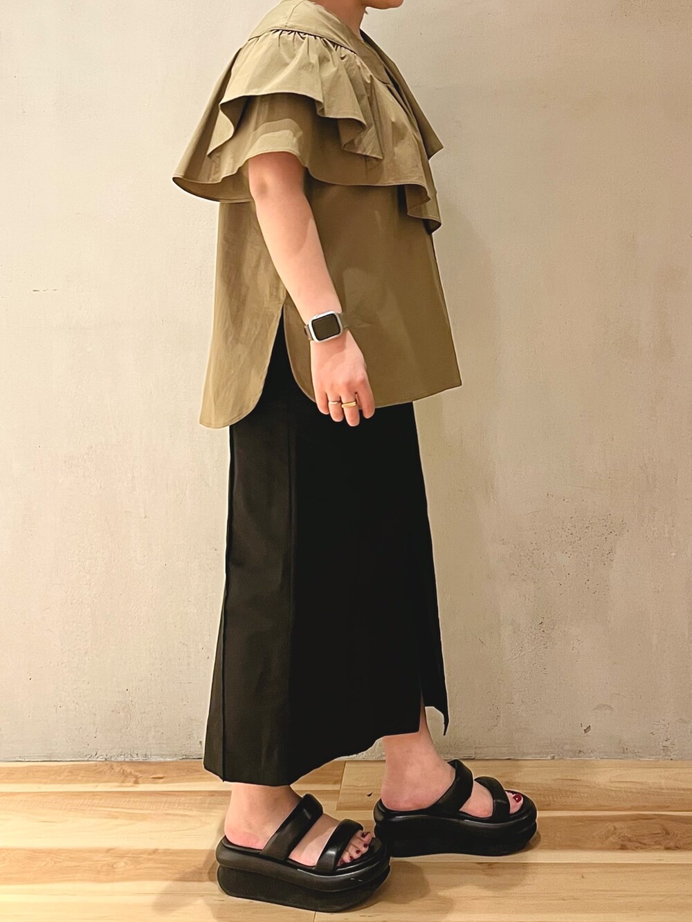 グリーン系のシャツ/ブラウス、ブラック系のスカート、ブラック系のサンダルを着用したレディースの冬コーディネートの2枚目の写真