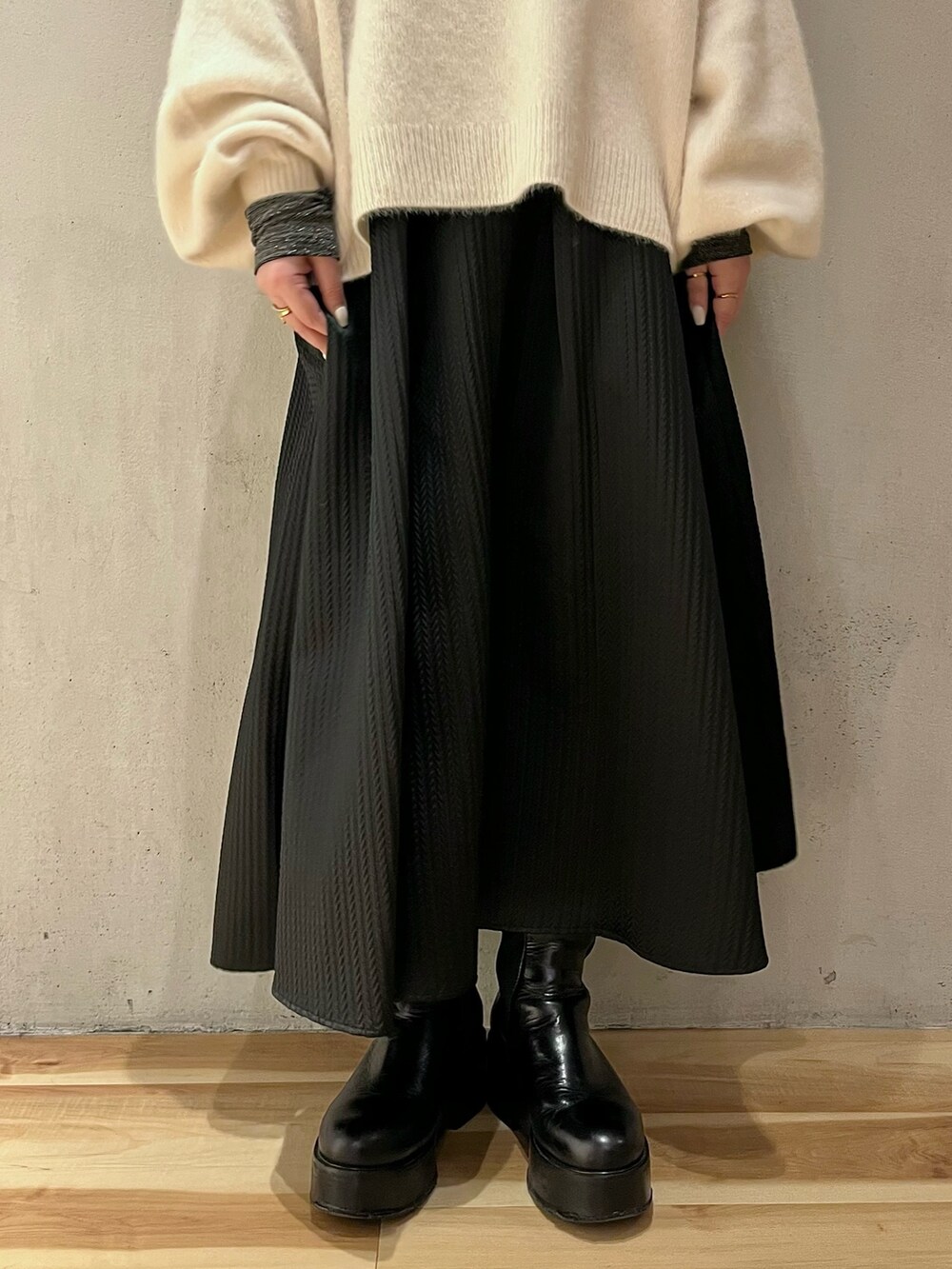 ホワイト系のニット/セーター、シルバー系のTシャツ/カットソー、ブラック系のスカートを着用したレディースの冬コーディネートの8枚目の写真