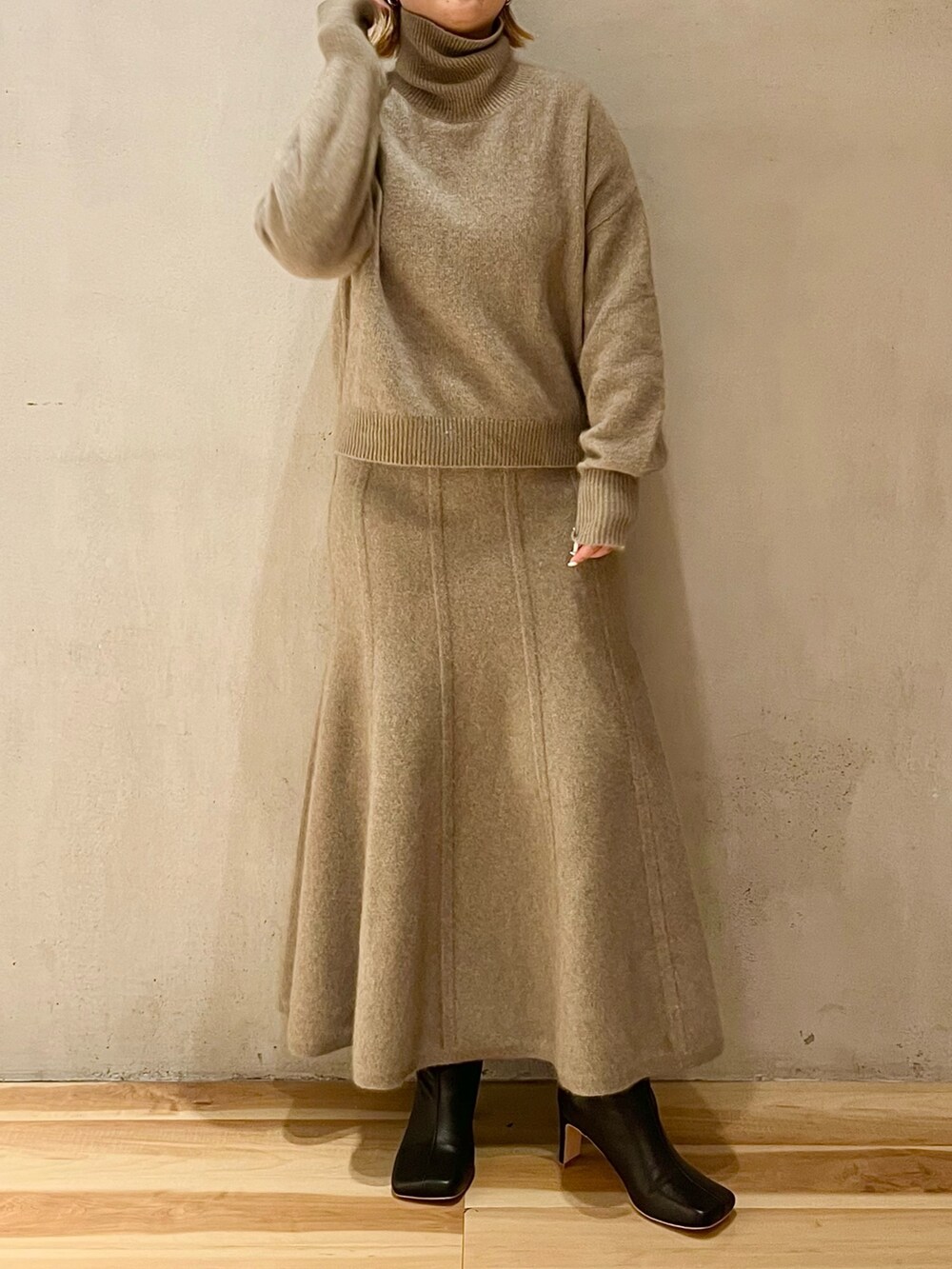 ベージュ系のニット/セーター、ベージュ系のスカート、ブラック系のブーツを着用したレディースの秋コーディネートの3枚目の写真
