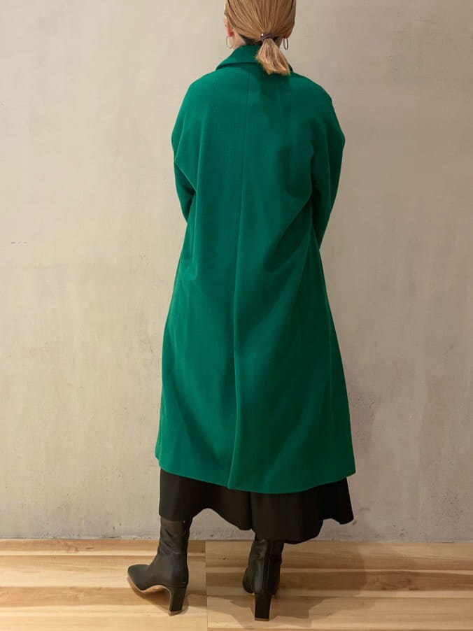 ブラック系のジャンパースカート、ブラウン系のニット/セーター、グリーン系のチェスターコートを着用したレディースの秋コーディネートの3枚目の写真