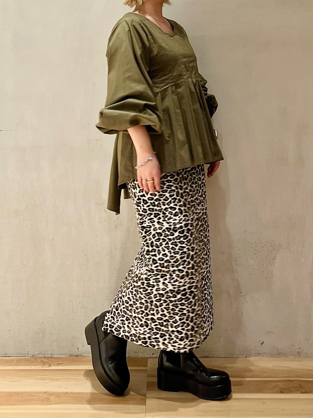 グリーン系のシャツ/ブラウス、ホワイト系のスカート、ブラック系のブーツを着用したレディースの秋コーディネートの3枚目の写真