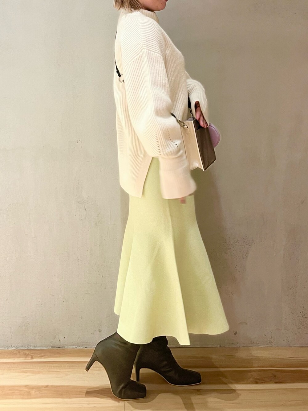 ホワイト系のニット/セーター、ベージュ系のショルダーバッグ、グリーン系のスカートを着用したレディースの冬コーディネートの2枚目の写真