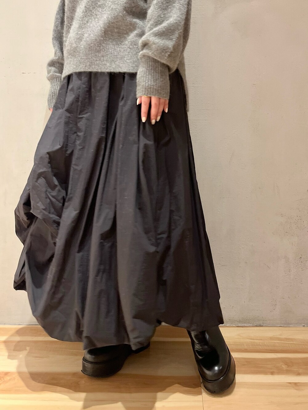 グレー系のニット/セーター、ブラック系のスカート、ブラック系のブーツを着用したレディースの冬コーディネートの9枚目の写真