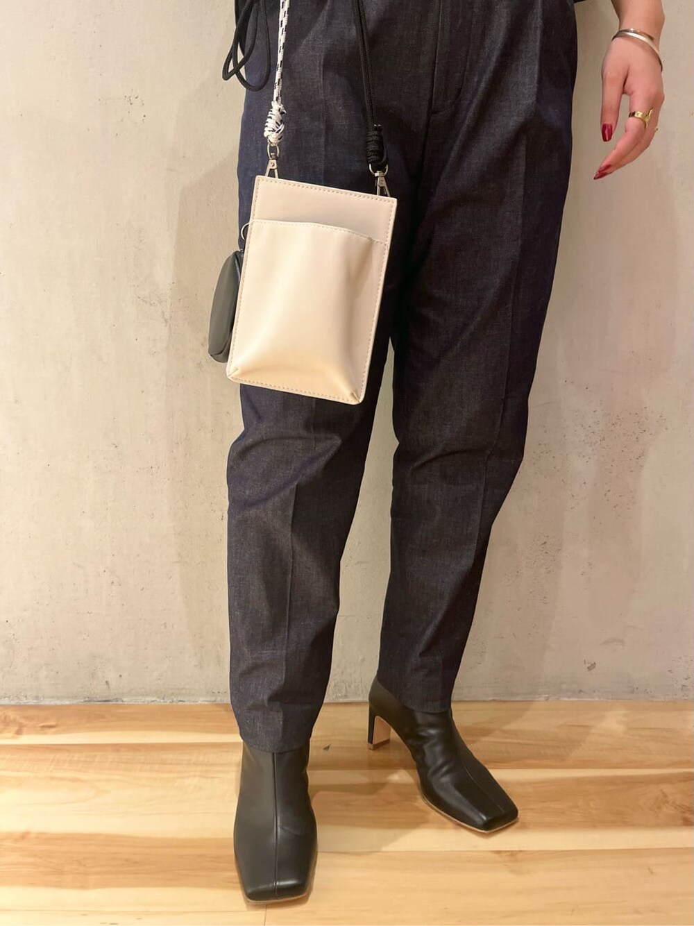 ホワイト系のショルダーバッグ、イエロー系のカーディガン/ボレロ、ブラック系のブーツを着用したレディースの秋コーディネートの10枚目の写真