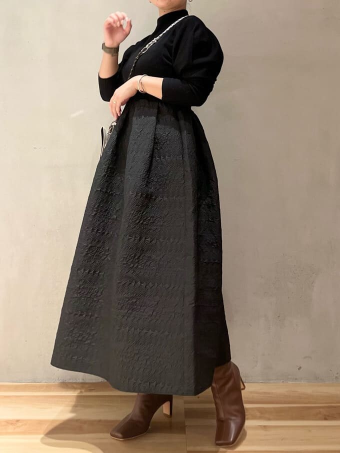 ベージュ系のショルダーバッグ、ブラウン系のブーツ、ブラック系のワンピースを着用したレディースの秋コーディネートの2枚目の写真