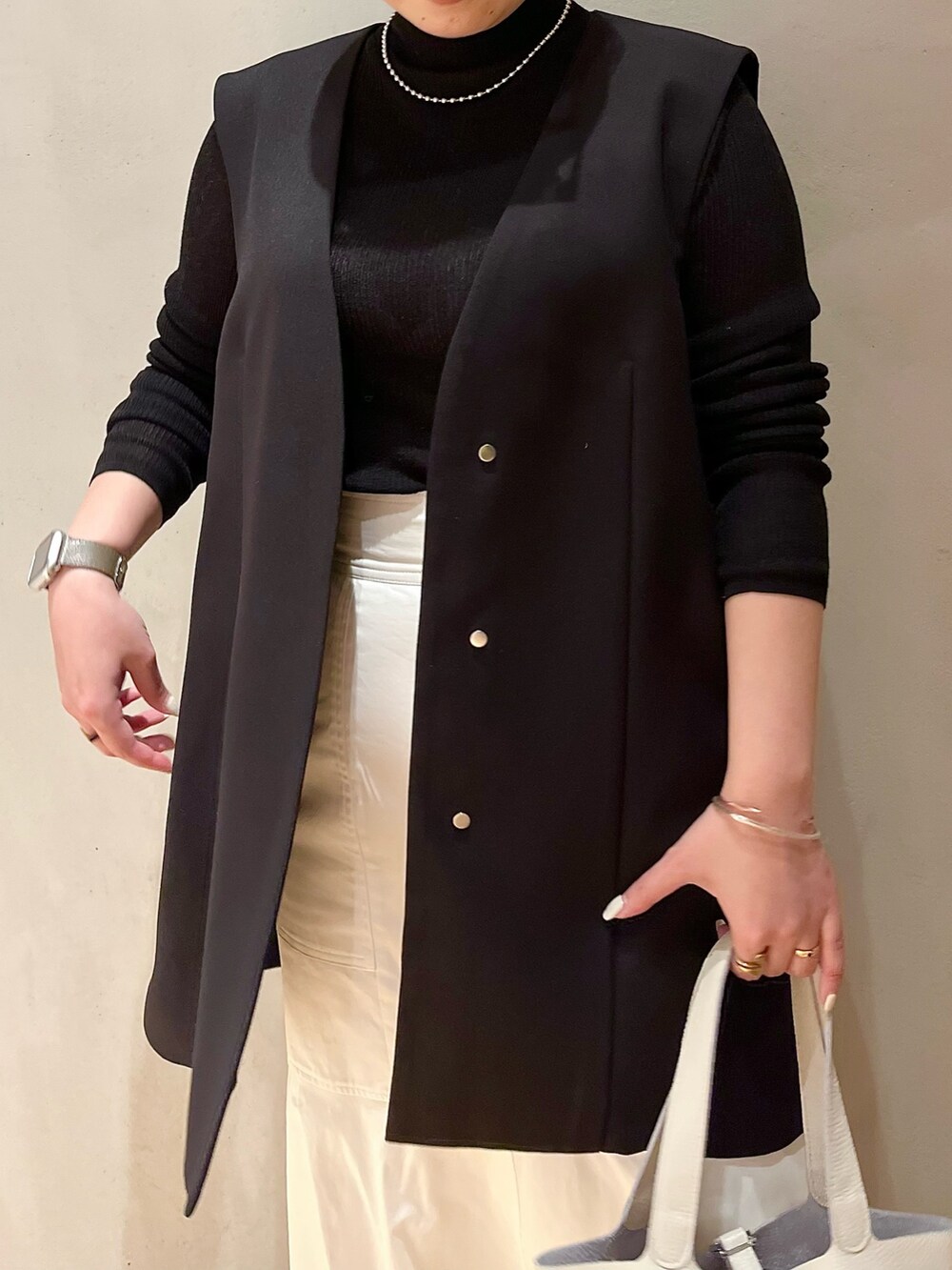 ホワイト系のスカート、ホワイト系のハンドバッグ、ブラック系のテーラードジャケットを着用したレディースの冬コーディネートの5枚目の写真