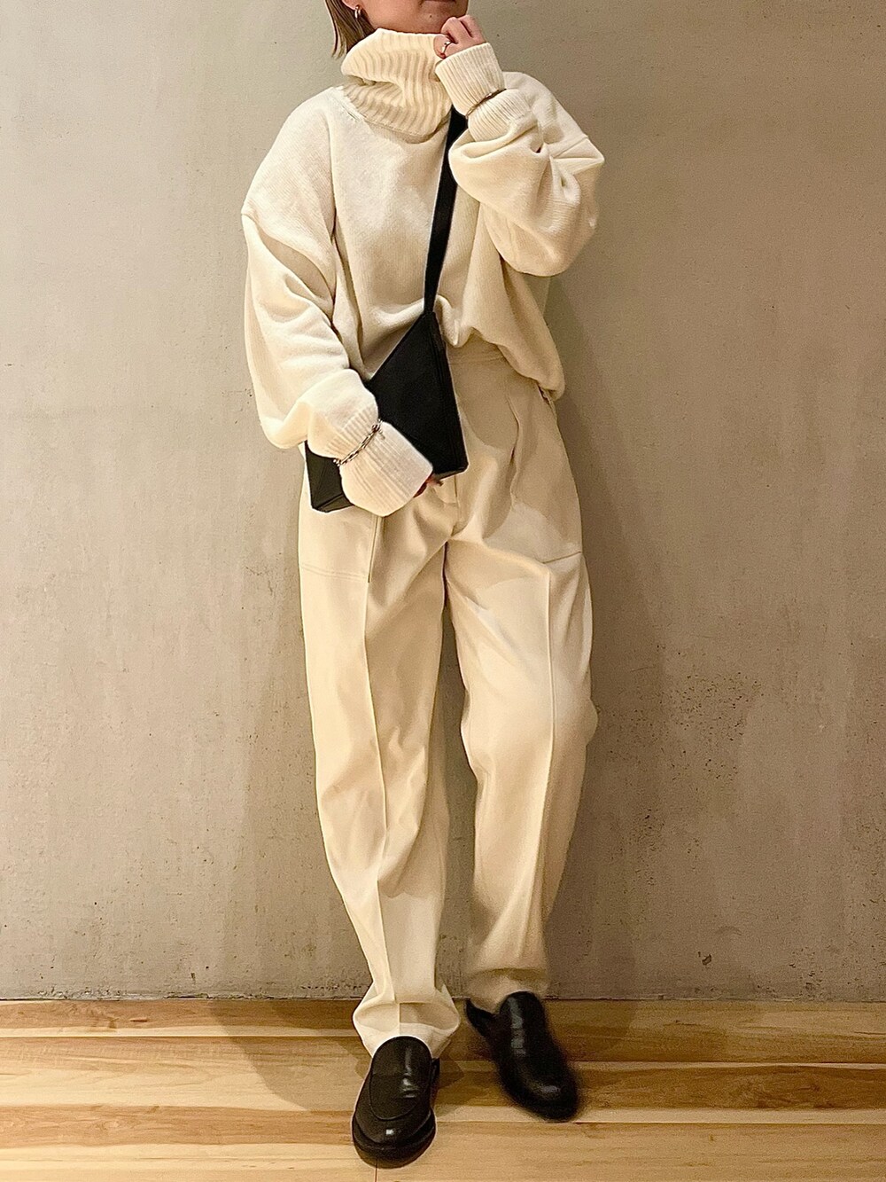 ホワイト系のニット/セーター、ホワイト系のその他パンツ、ブラック系のハンドバッグを着用したレディースの夏コーディネートの5枚目の写真