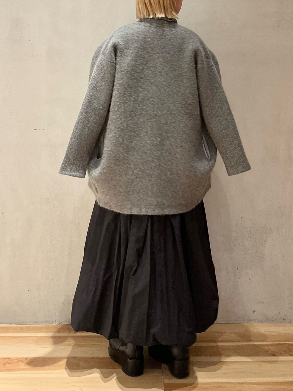 グレー系のニット/セーター、ブラック系のスカート、ブラック系のブーツを着用したレディースの冬コーディネートの3枚目の写真