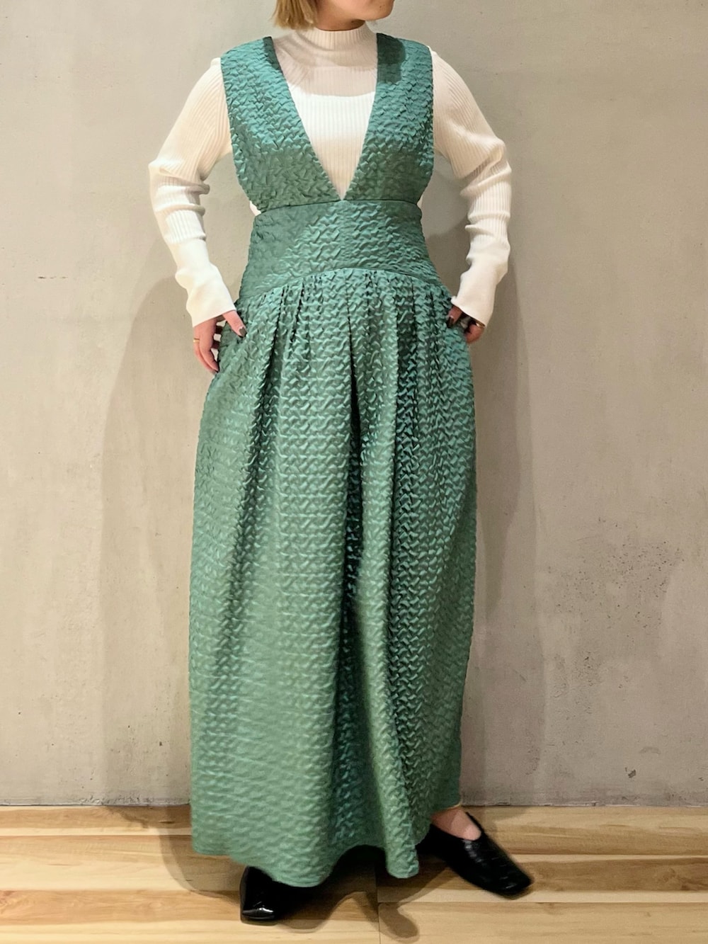 ブラック系のノーカラージャケット、グリーン系のジャンパースカート、ホワイト系のニット/セーターを着用したレディースの秋コーディネートの5枚目の写真