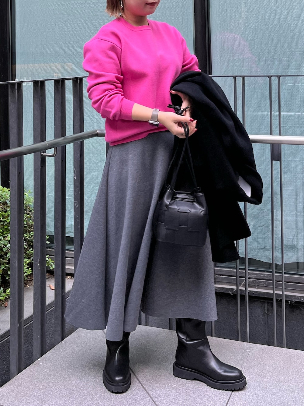ピンク系のニット/セーター、ブラック系のチェスターコート、グレー系のスカートを着用したレディースの冬コーディネートの2枚目の写真