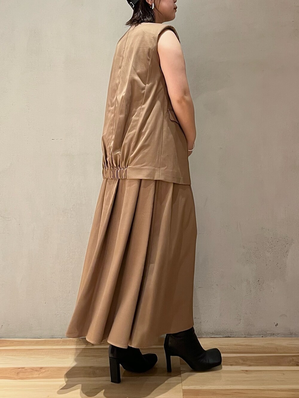 ベージュ系のワンピース、ブラック系のブーツ、ブラック系のキャップを着用したレディースの夏コーディネートの5枚目の写真