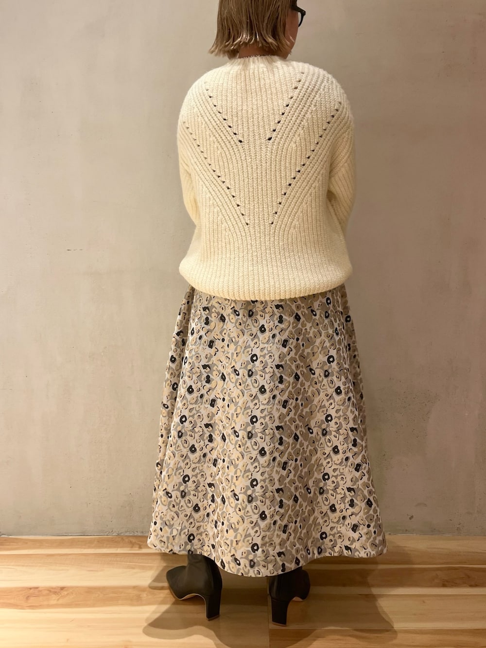 ベージュ系のスカート、ブラック系のハンドバッグ、ホワイト系のニット/セーターを着用したレディースの冬コーディネートの3枚目の写真