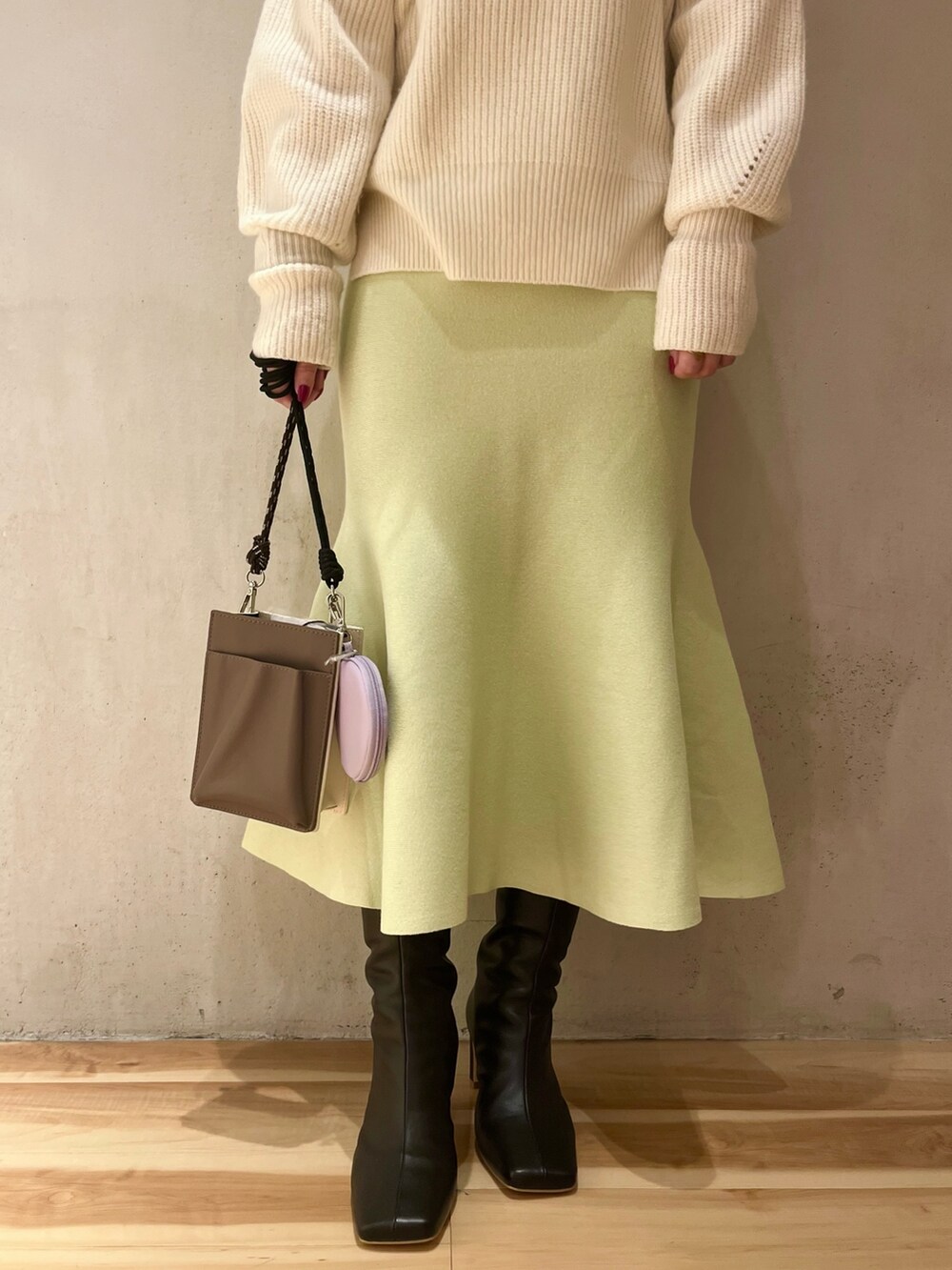 ホワイト系のニット/セーター、ベージュ系のショルダーバッグ、グリーン系のスカートを着用したレディースの冬コーディネートの5枚目の写真