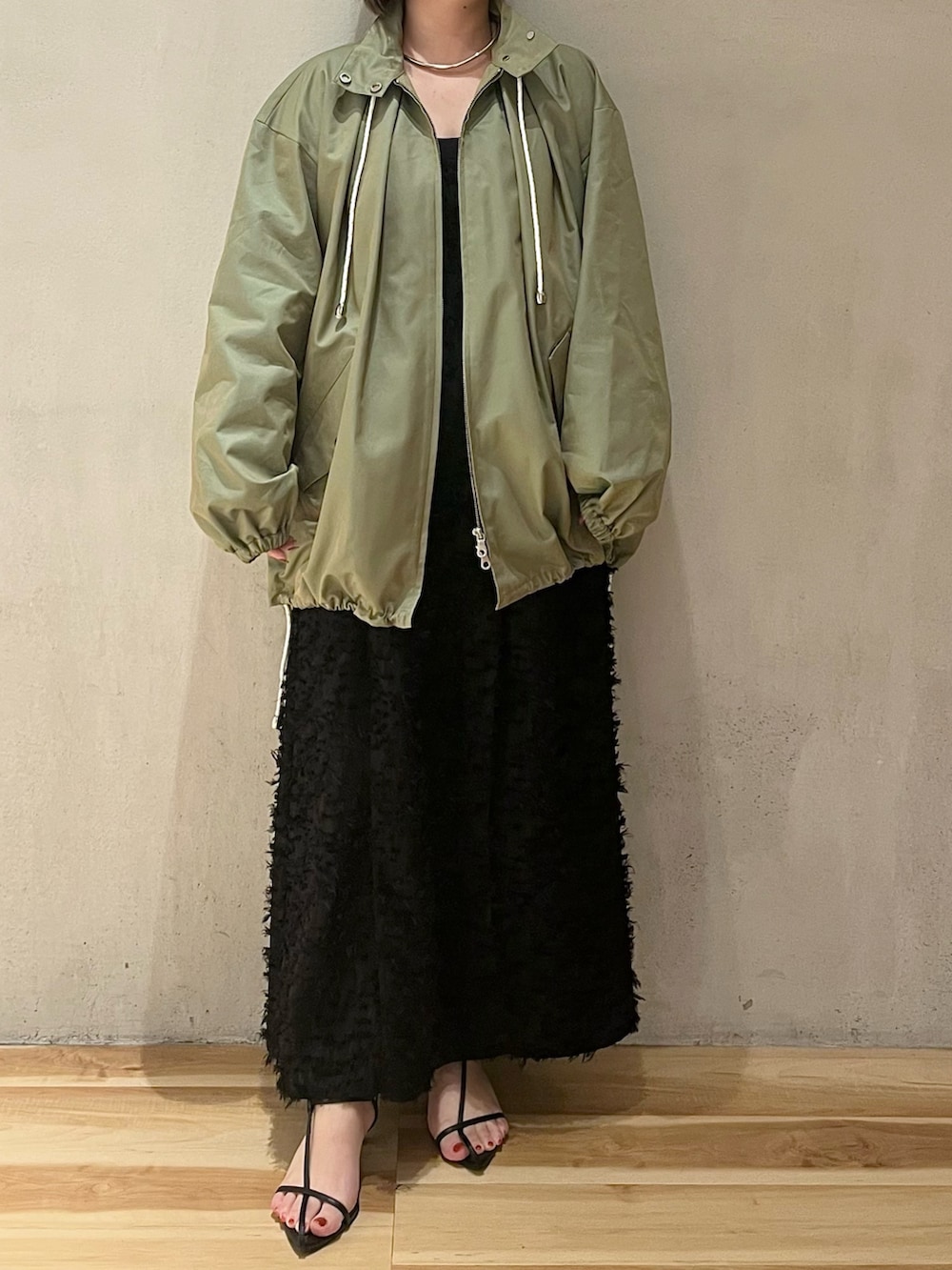 グリーン系のミリタリージャケット、ブラック系のワンピースを着用したレディースの春コーディネートの2枚目の写真
