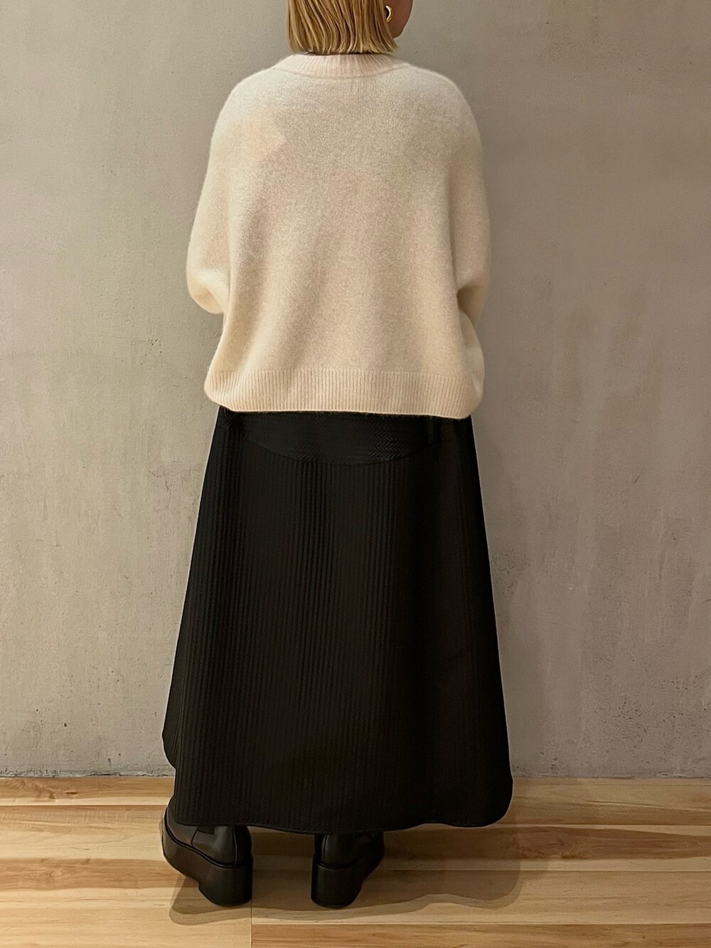 ホワイト系のニット/セーター、シルバー系のTシャツ/カットソー、ブラック系のスカートを着用したレディースの冬コーディネートの3枚目の写真