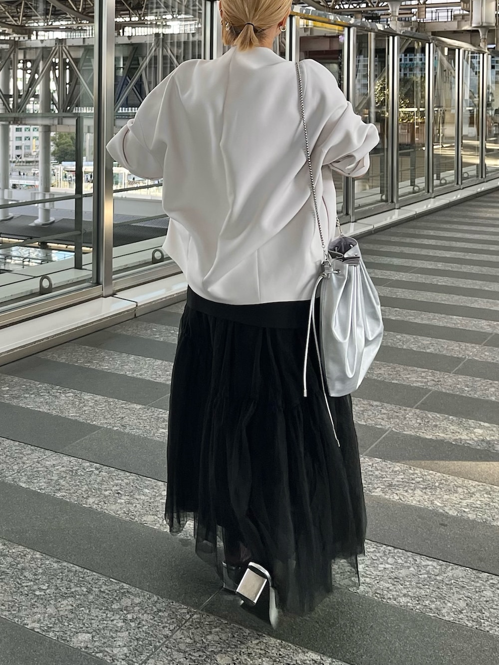 ベージュ系のノーカラーコート、ブラック系のタンクトップ、ブラック系のスカートを着用したレディースの冬コーディネートの4枚目の写真