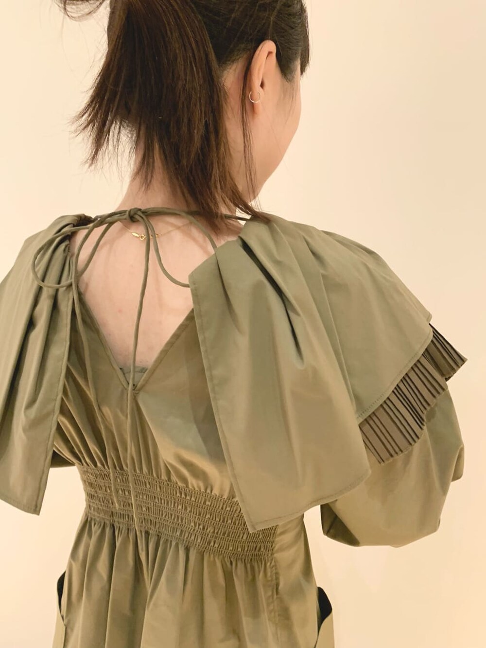 ベージュ系のノーカラーコート、ベージュ系のワンピースを着用したレディースの冬コーディネートの5枚目の写真