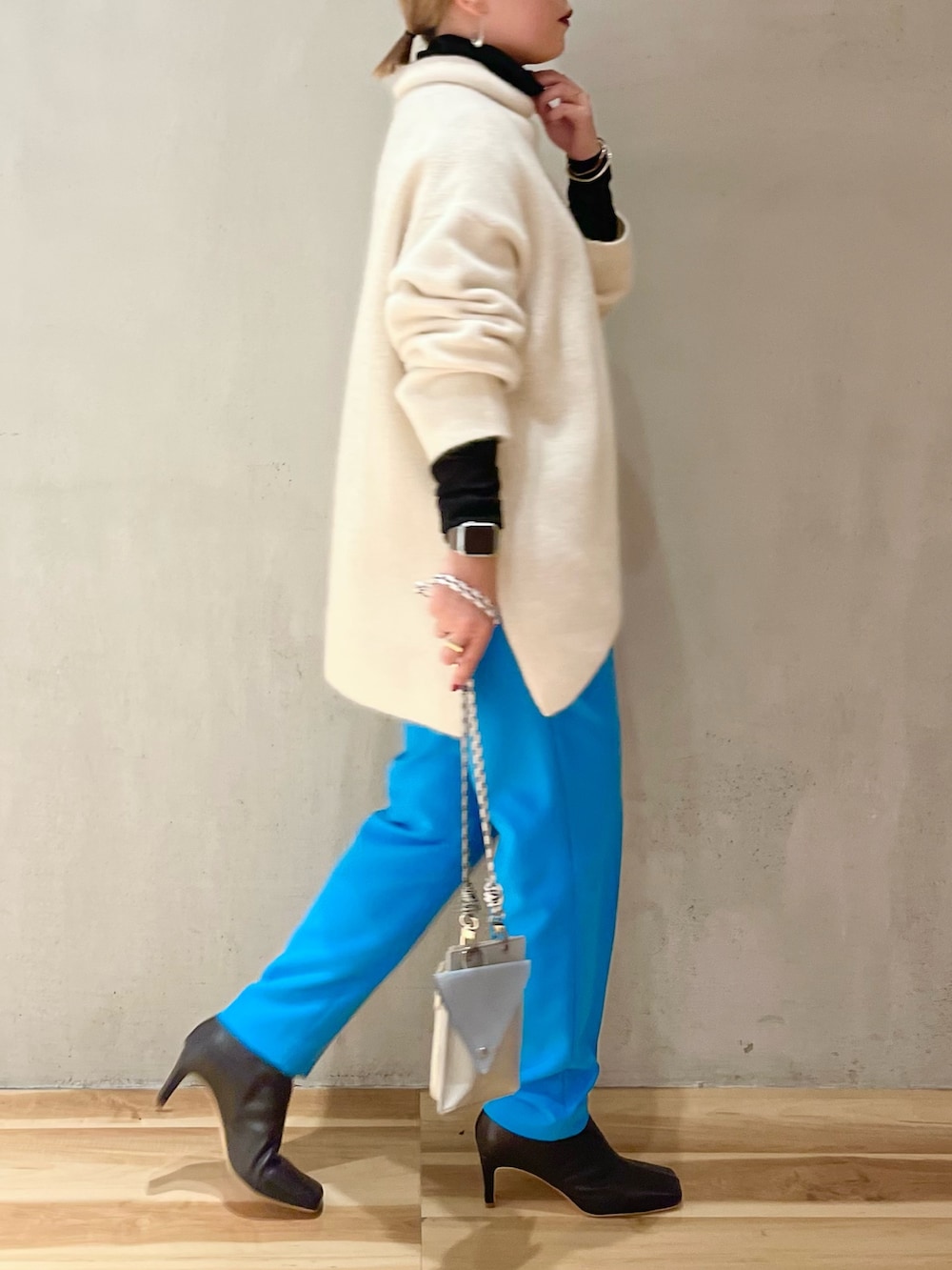 ブラック系のブーツ、ブラック系のTシャツ/カットソー、ホワイト系のニット/セーターを着用したレディースの冬コーディネートの2枚目の写真