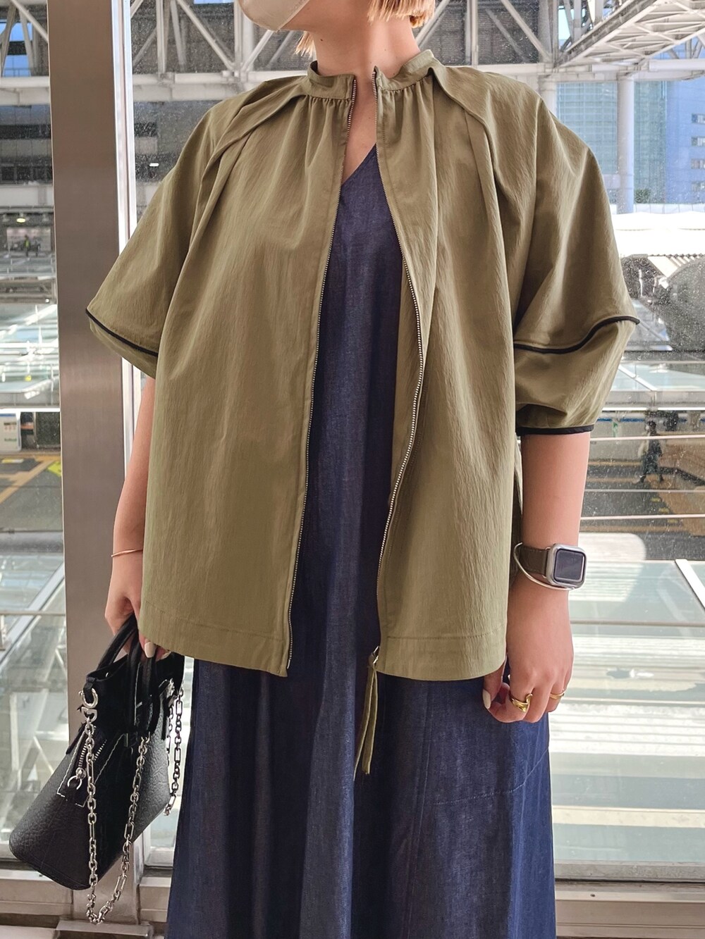 グリーン系のブルゾン、ブルー系のワンピース、ブラック系のスニーカーを着用したレディースの春コーディネートの3枚目の写真