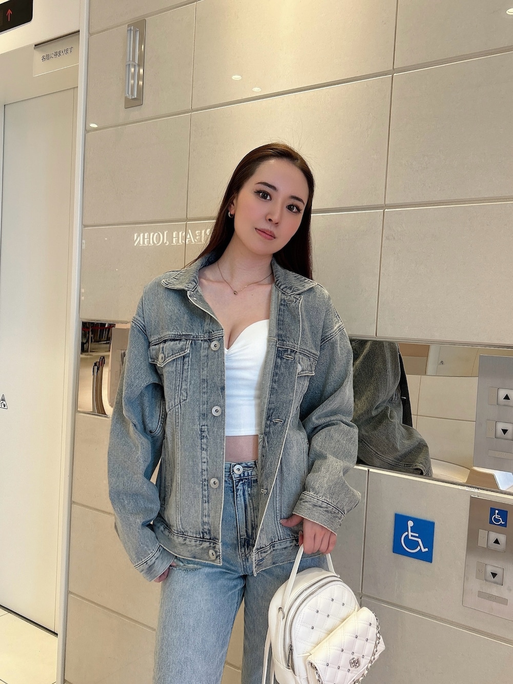 ホワイト系のパンプス、ブルー系のデニムジャケット、ホワイト系のキャミソールを着用したレディースの春コーディネートの4枚目の写真