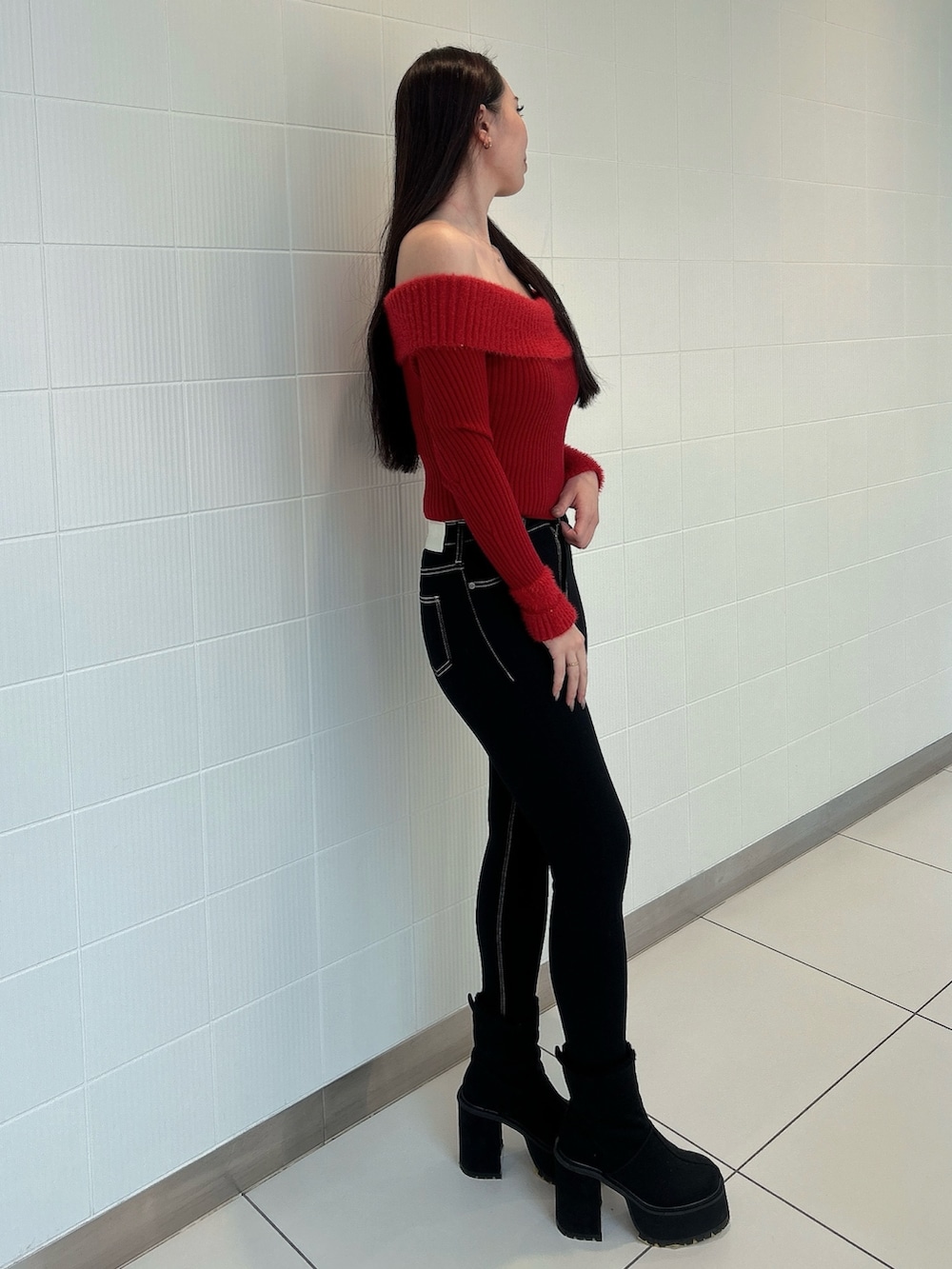 レッド系のニット/セーター、ブルー系のデニムパンツ、ブラック系のブーツを着用したレディースの冬コーディネートの2枚目の写真