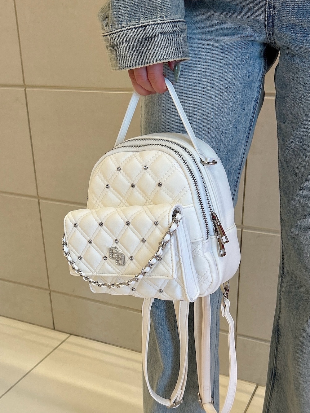 ホワイト系のパンプス、ブルー系のデニムジャケット、ホワイト系のキャミソールを着用したレディースの春コーディネートの7枚目の写真