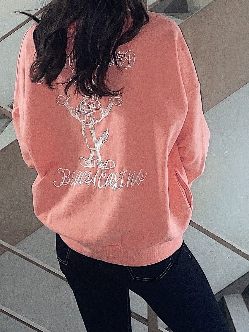 オレンジ系のスウェット、ブラック系のその他シューズ、ブラック系のデニムパンツを着用したレディースの冬コーディネートの3枚目の写真