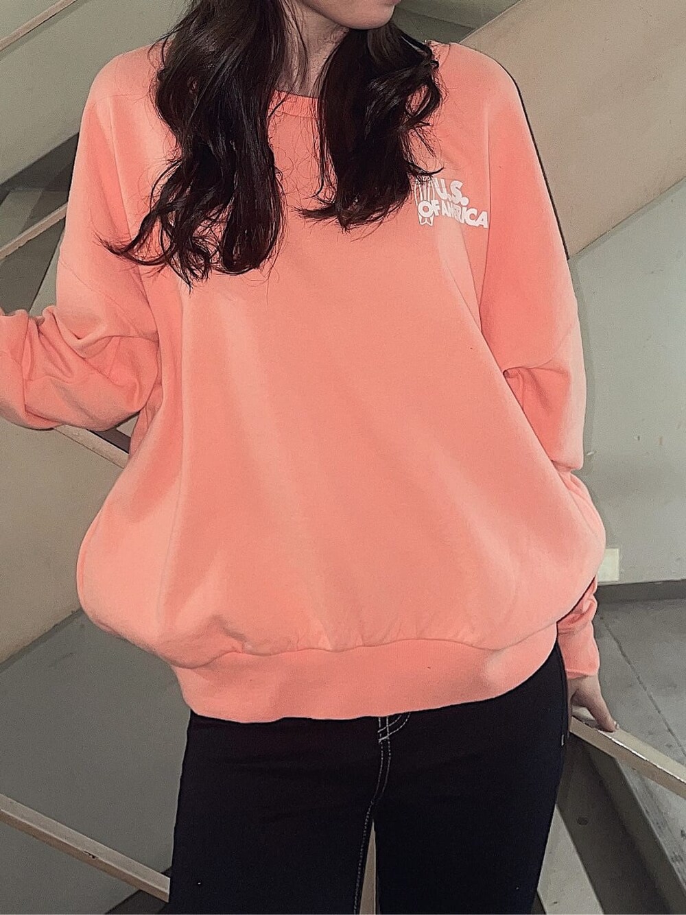 オレンジ系のスウェット、ブラック系のその他シューズ、ブラック系のデニムパンツを着用したレディースの冬コーディネートの2枚目の写真