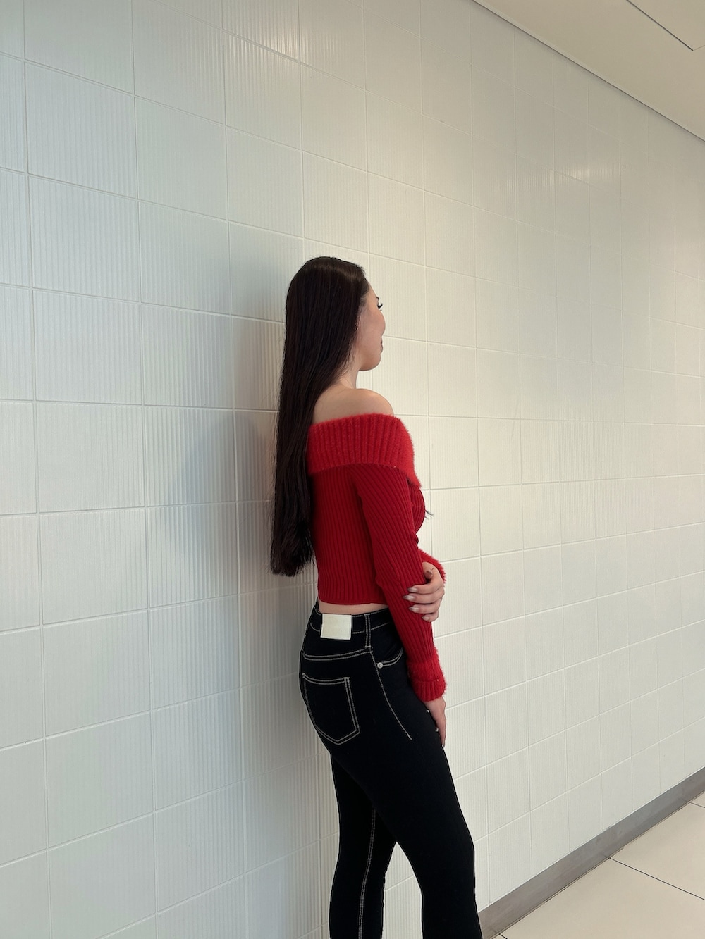 レッド系のニット/セーター、ブルー系のデニムパンツ、ブラック系のブーツを着用したレディースの冬コーディネートの5枚目の写真