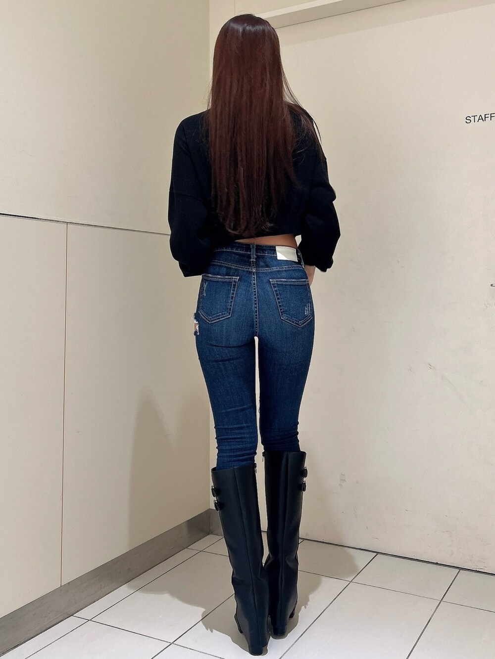 ブラック系のニット/セーター、ブラック系のブーツ、ブルー系のデニムパンツを着用したレディースの秋コーディネートの3枚目の写真