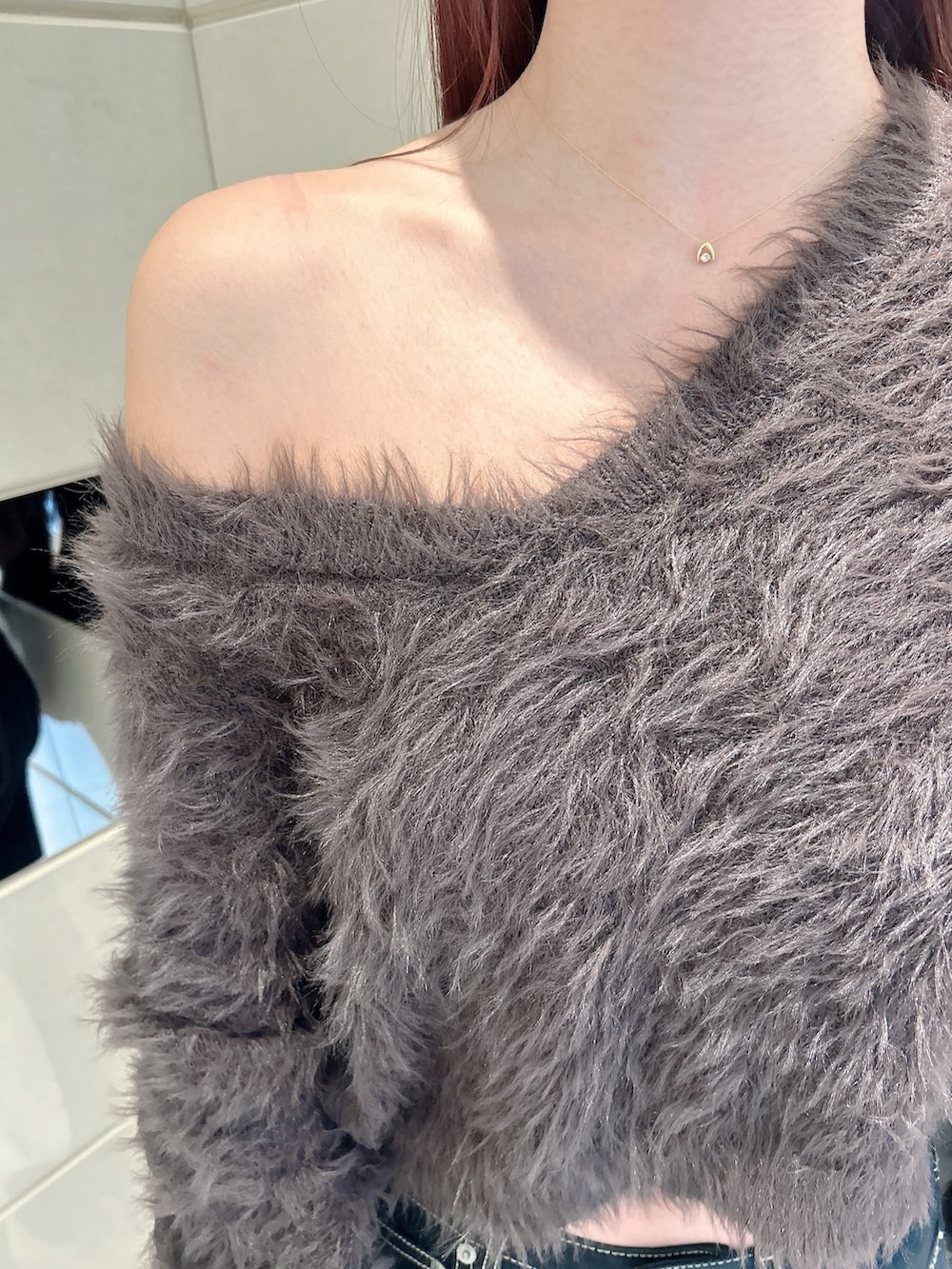 グレー系のニット/セーター、ブラック系のデニムパンツ、ブラック系のブーツを着用したレディースの冬コーディネートの7枚目の写真