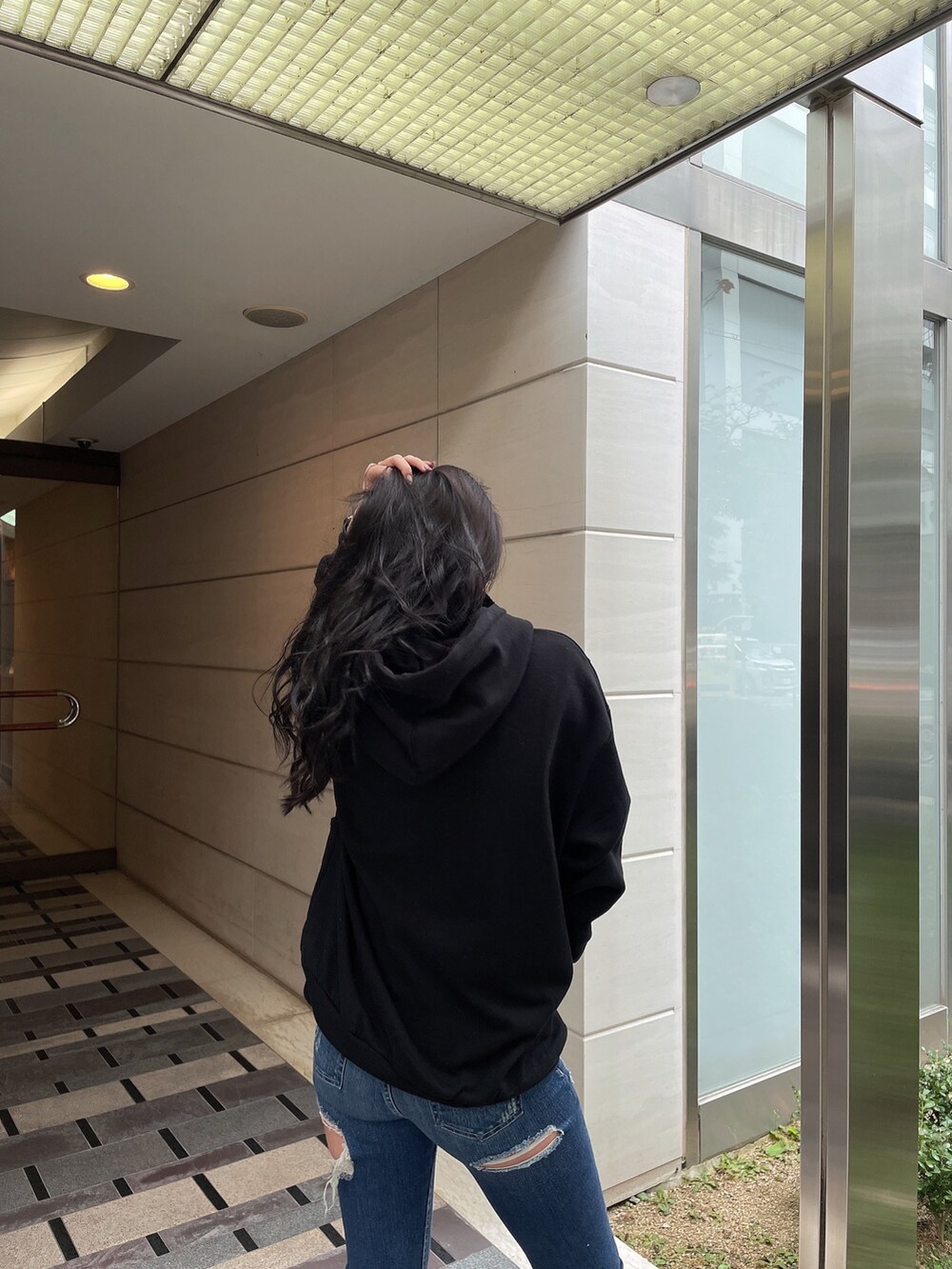 ブルー系のデニムパンツ、ブラック系のスウェット、ブラック系のパンプスを着用したレディースの冬コーディネートの4枚目の写真