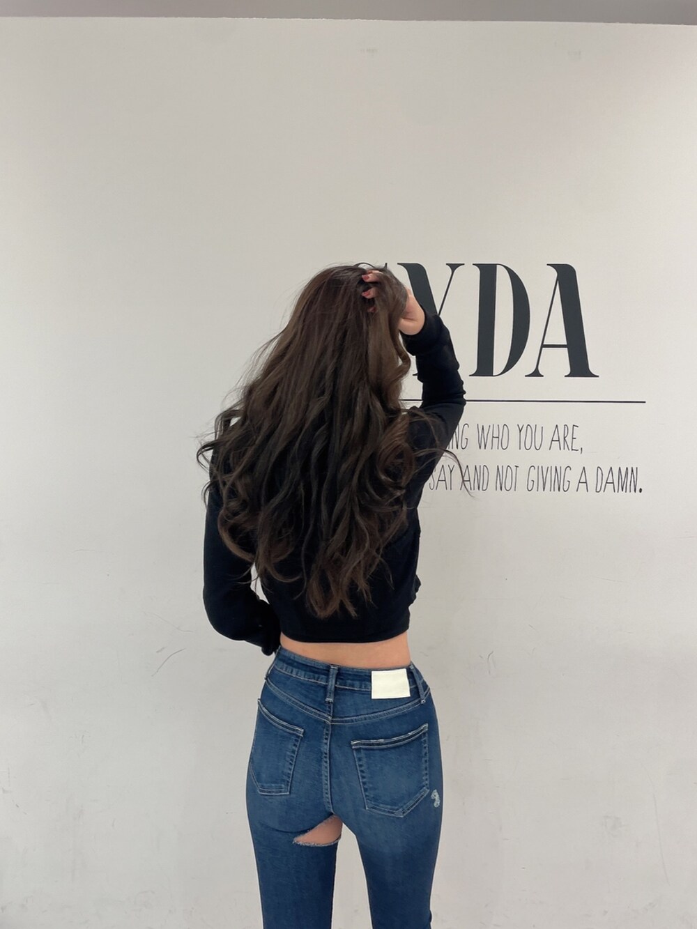 ブラック系のパーカー、ホワイト系のキャミソール、ブルー系のデニムパンツを着用したレディースの冬コーディネートの4枚目の写真