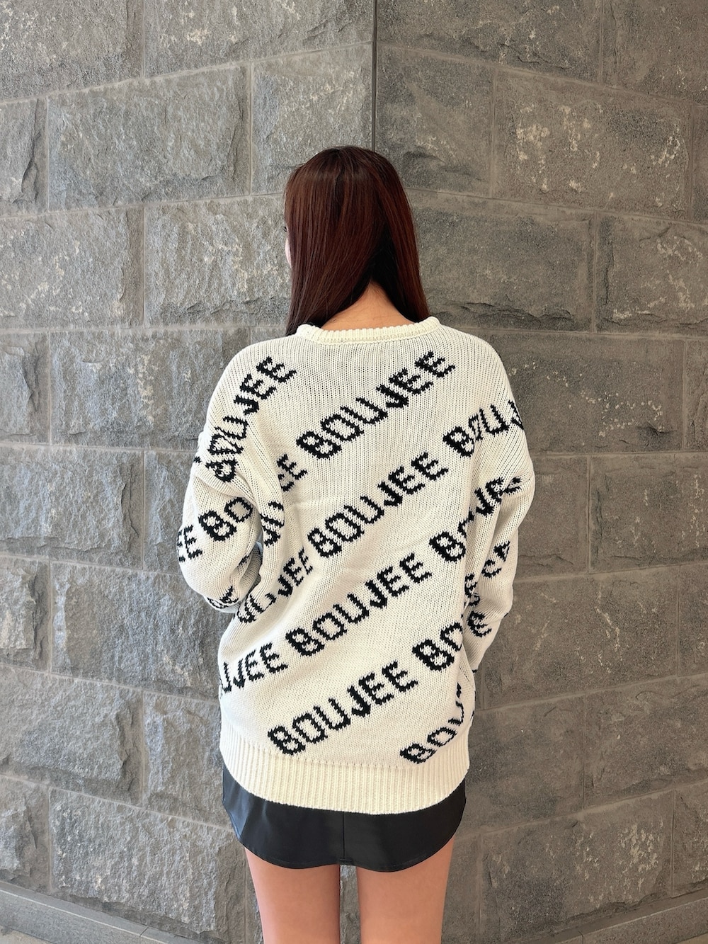 ブラック系のニット/セーター、ブラック系のスカート、ブラック系のブーツを着用したレディースの秋コーディネートの6枚目の写真