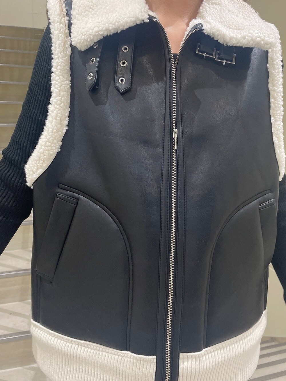 ブラック系のベスト、ブラック系のスカート、ブラック系のブーツを着用したレディースの秋コーディネートの6枚目の写真