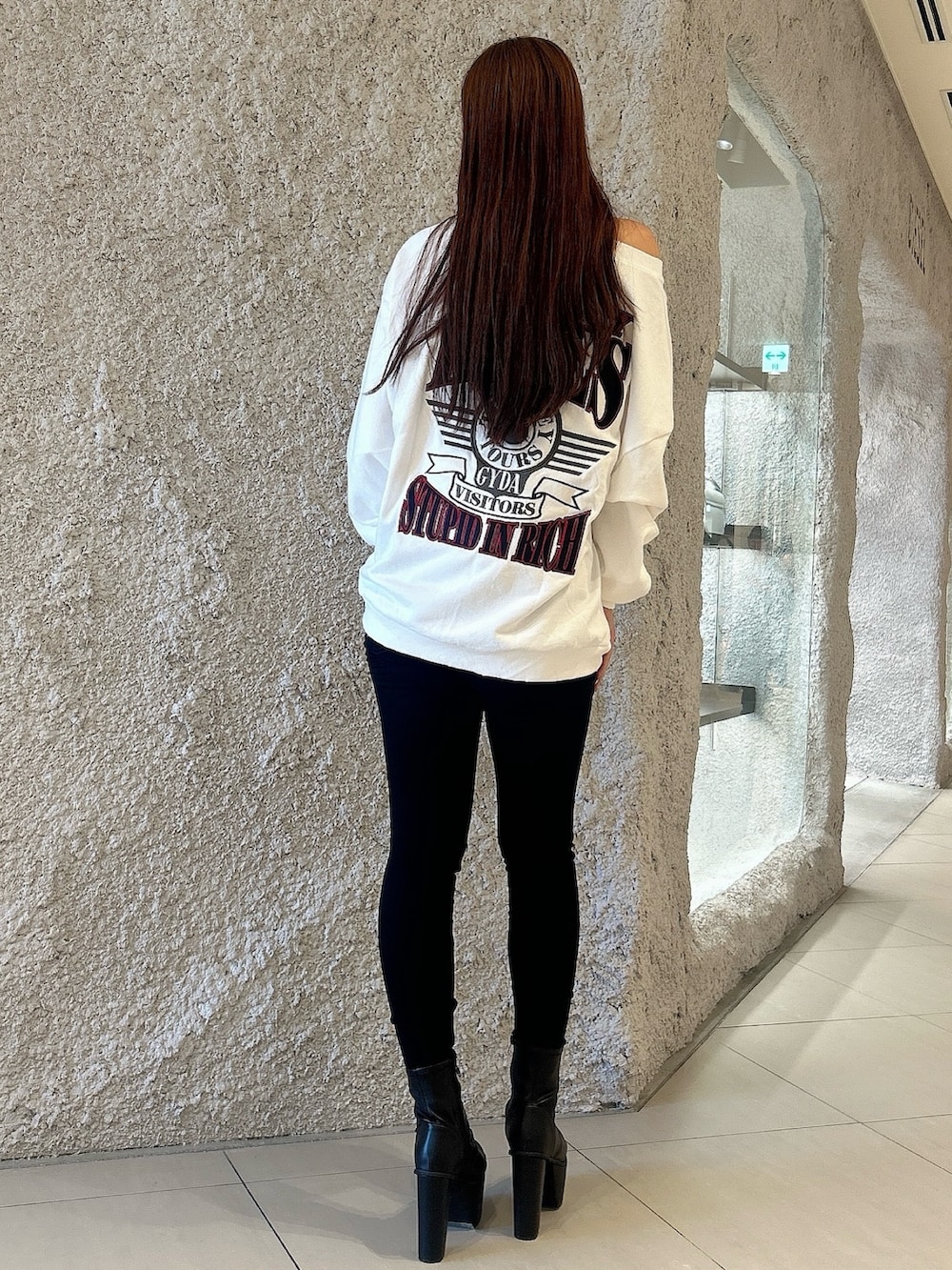 ホワイト系のスウェット、ブラック系のデニムパンツ、ブラック系のブーツを着用したレディースの秋コーディネートの3枚目の写真