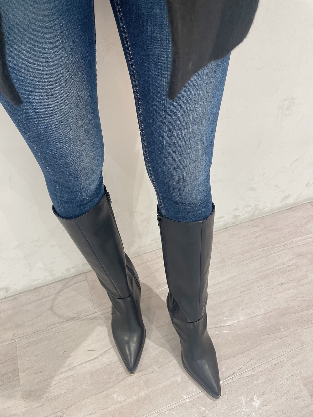 ブラック系のブーツ、ブルー系のデニムパンツ、ブラック系のチェスターコートを着用したレディースの冬コーディネートの7枚目の写真