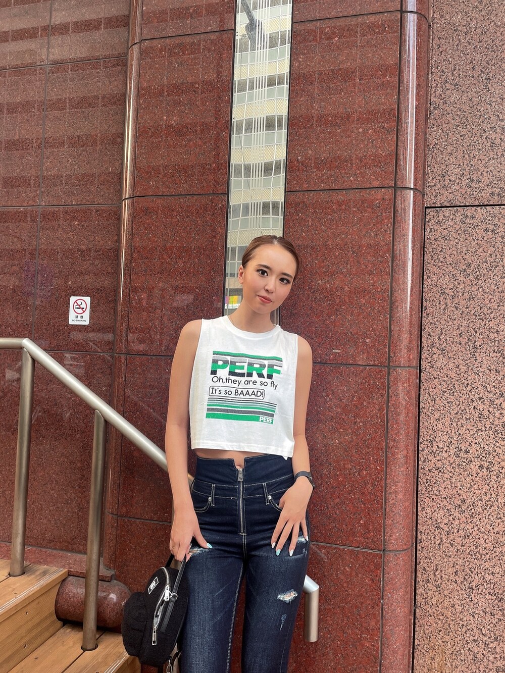 ホワイト系のタンクトップ、ブルー系のデニムパンツ、ブラック系のバックパック/リュックを着用したレディースの夏コーディネートの4枚目の写真