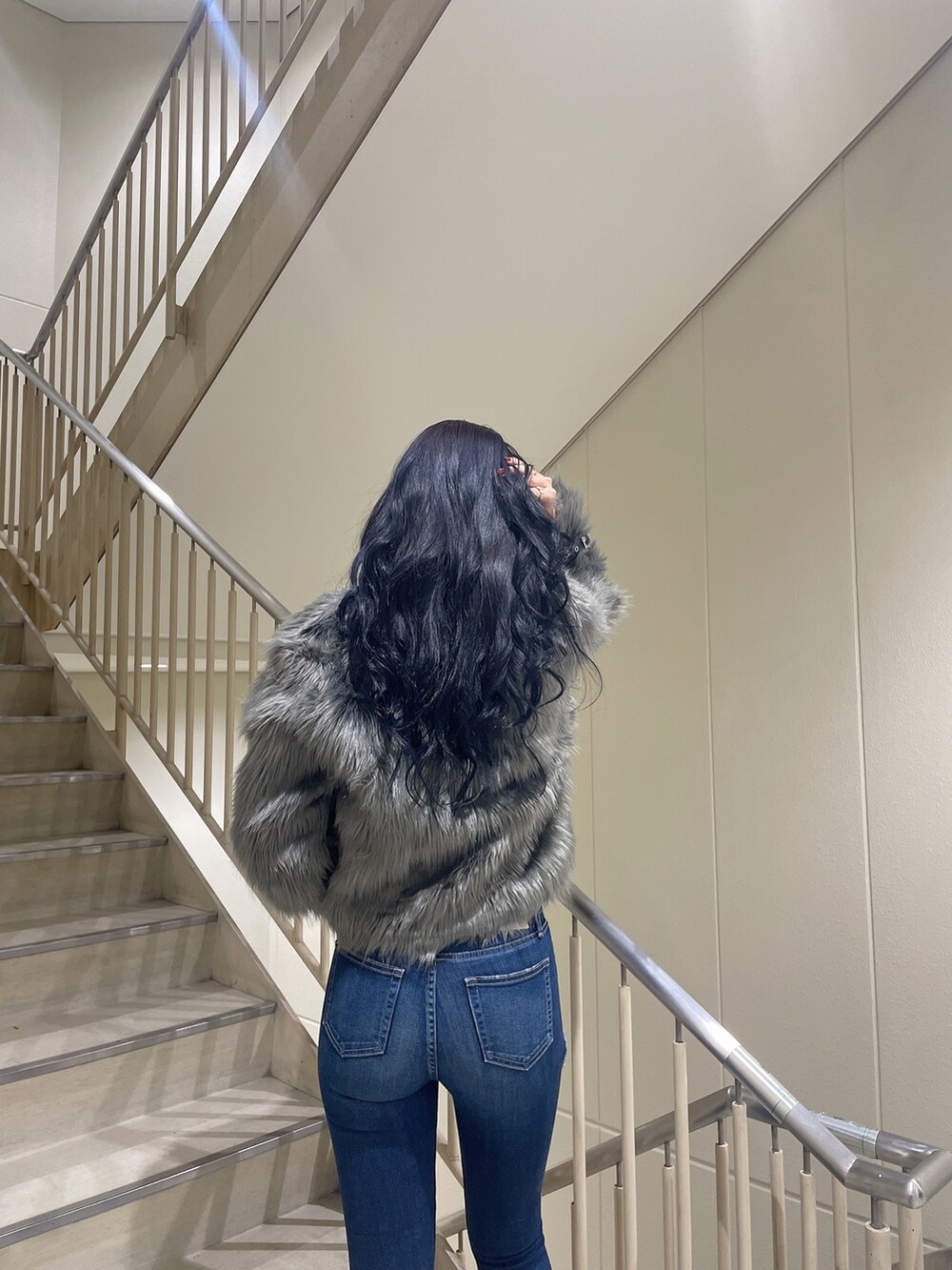 ブルー系のデニムパンツ、ホワイト系のニット/セーター、グレー系のライダースジャケットを着用したレディースの秋コーディネートの5枚目の写真