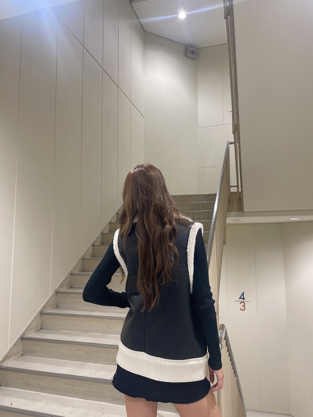 ブラック系のベスト、ブラック系のスカート、ブラック系のブーツを着用したレディースの秋コーディネートの4枚目の写真