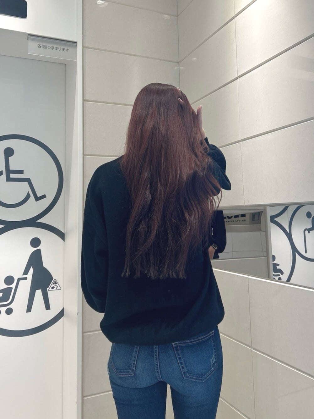 ブルー系のデニムパンツ、ホワイト系のパンプス、ブラック系のニット/セーターを着用したレディースの冬コーディネートの6枚目の写真