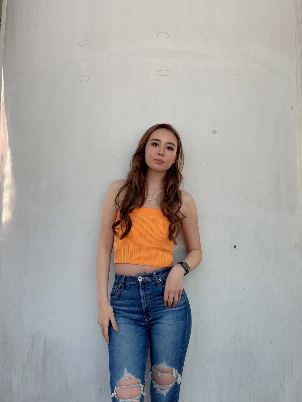 オレンジ系のニット/セーター、ブルー系のデニムパンツ、ベージュ系のサンダルを着用したレディースの春コーディネートの4枚目の写真