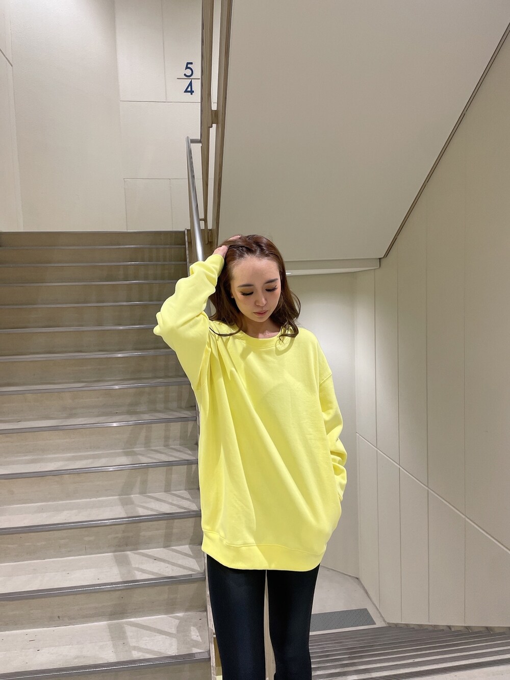 イエロー系のスウェット、ブラック系のブーツ、ブラック系のレギンス/スパッツを着用したレディースの秋コーディネートの3枚目の写真