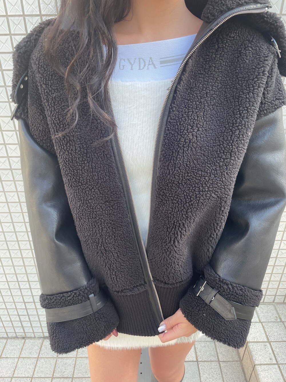 ブラック系のブルゾン、ホワイト系のワンピース、ブラック系のブーツを着用したレディースの冬コーディネートの5枚目の写真