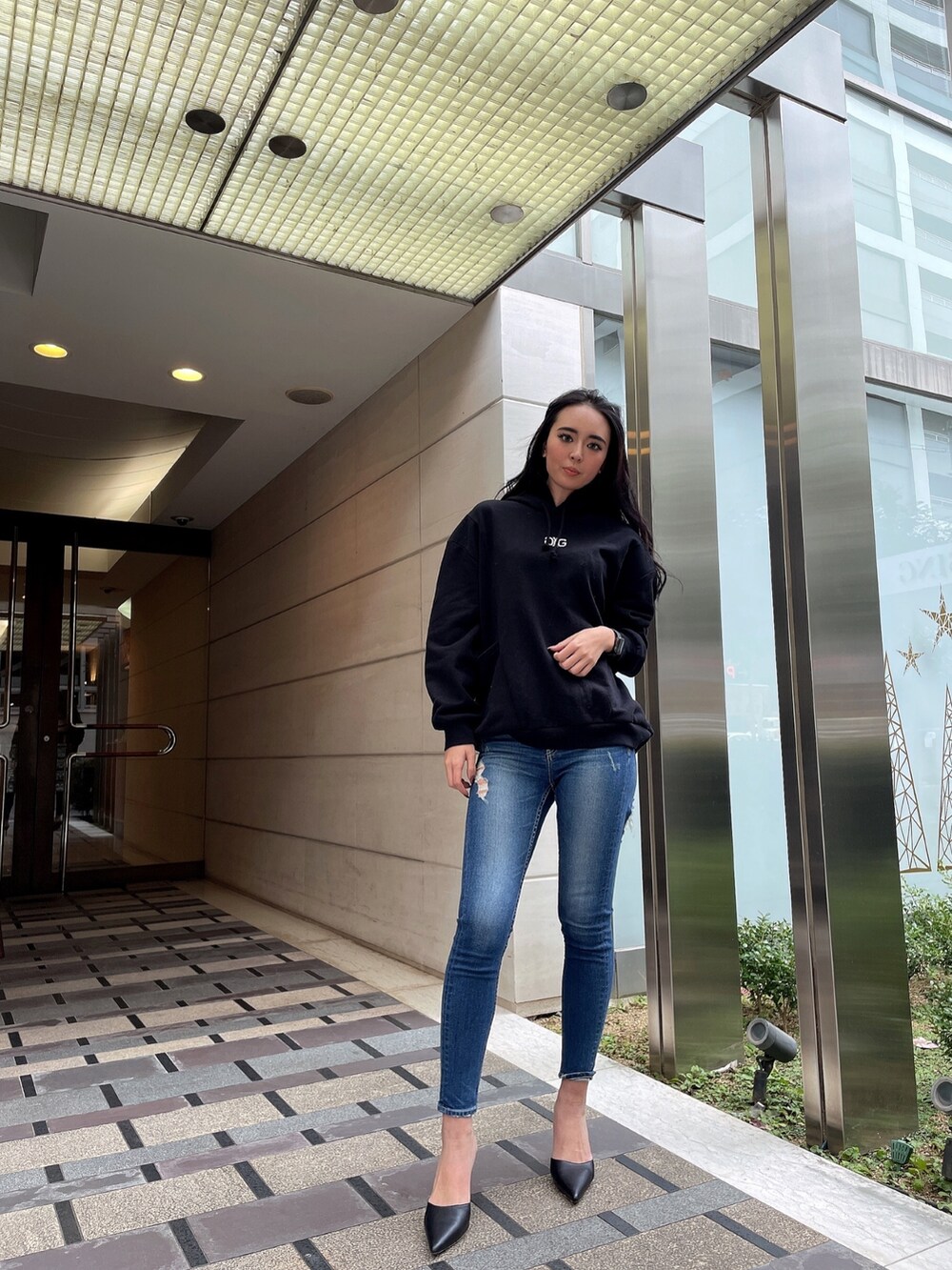 ブルー系のデニムパンツ、ブラック系のスウェット、ブラック系のパンプスを着用したレディースの冬コーディネートの2枚目の写真