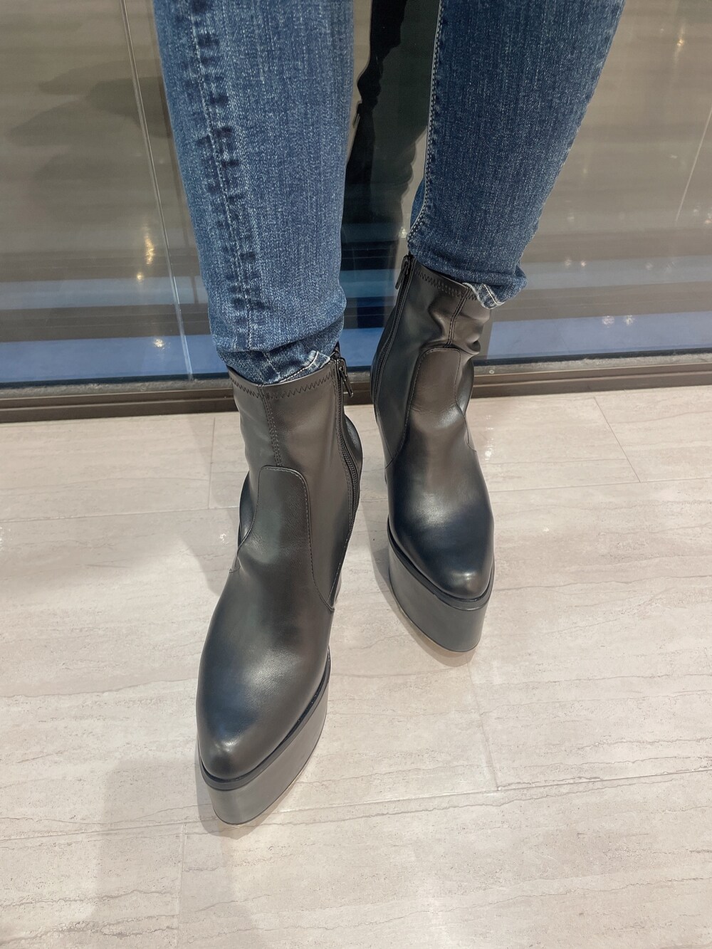 ホワイト系のTシャツ/カットソー、ブルー系のデニムパンツ、ブラック系のブーツを着用したレディースの冬コーディネートの7枚目の写真