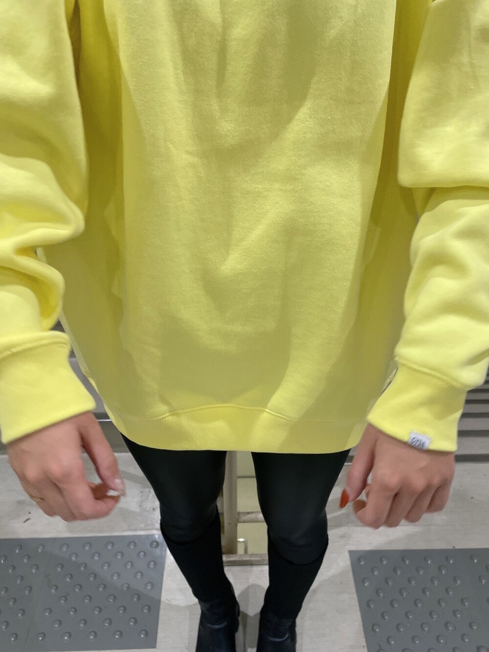 イエロー系のスウェット、ブラック系のブーツ、ブラック系のレギンス/スパッツを着用したレディースの秋コーディネートの4枚目の写真