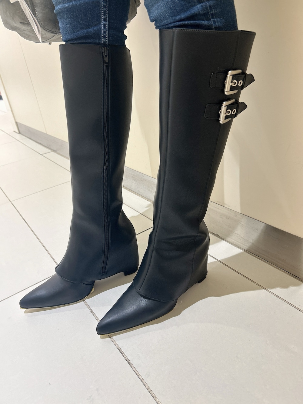 ブラック系のニット/セーター、ブラック系のブーツ、ブルー系のデニムパンツを着用したレディースの秋コーディネートの7枚目の写真