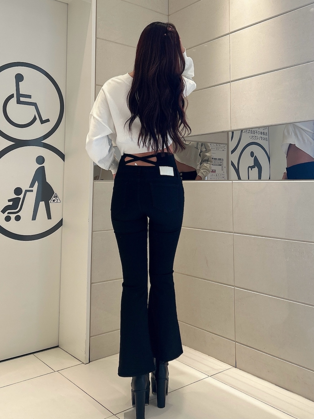 ホワイト系のニット/セーター、ブラック系のデニムパンツ、ブラック系のブーツを着用したレディースの冬コーディネートの3枚目の写真