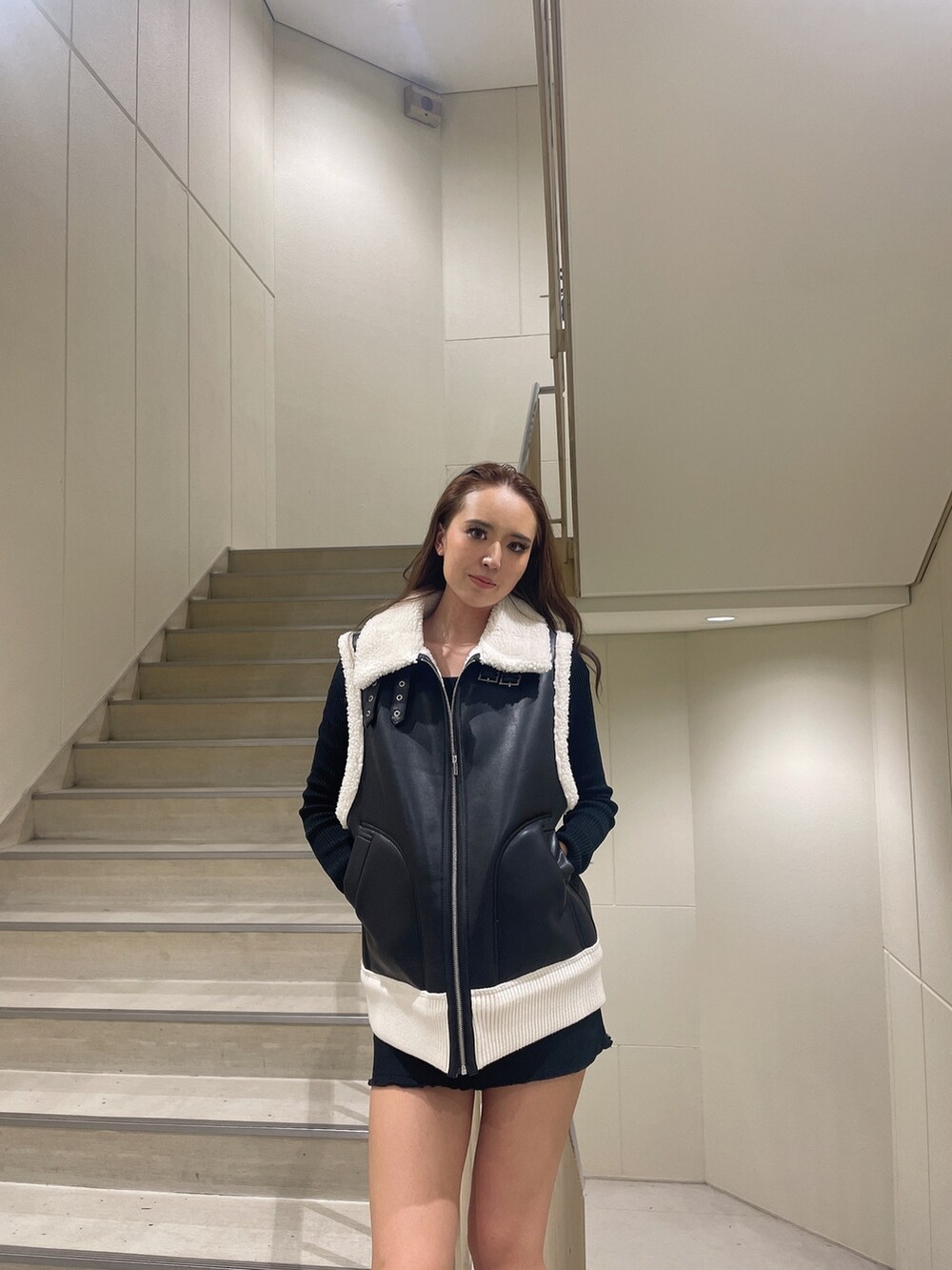 ブラック系のベスト、ブラック系のスカート、ブラック系のブーツを着用したレディースの秋コーディネートの3枚目の写真